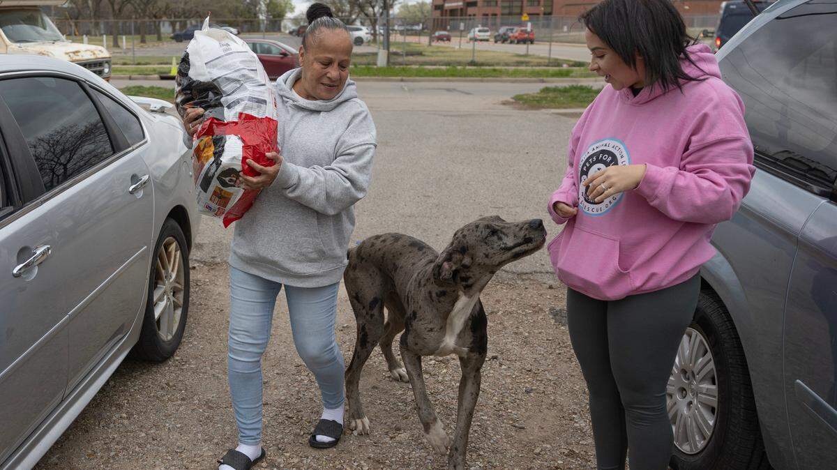 Maria Montoya, left, and Kylee Wallentine deliver dog food to a family in Planeview. The two drive through impoverished neighborhoods and homeless encampments to hand out pet food to those in need.