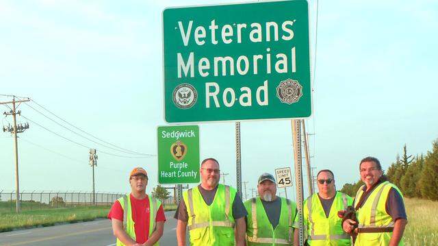 A public works crew installed one of ten Purple Heart county signs on Rock Road after Sedgwick County was named a Purple Heart County.