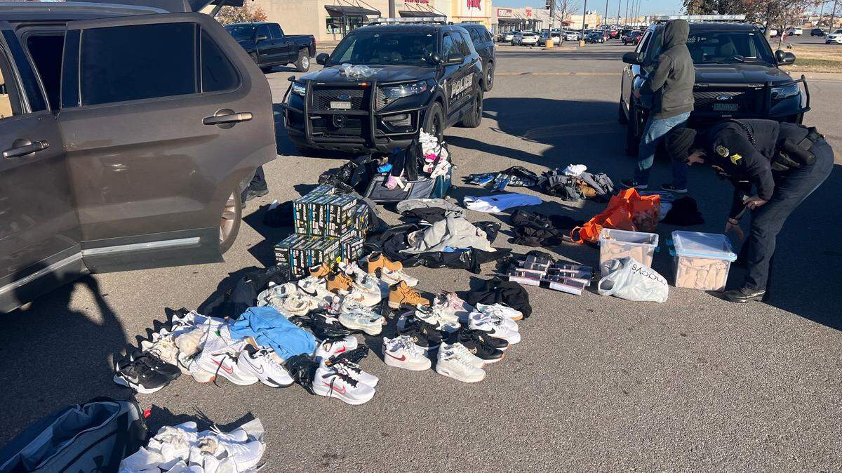 Police officers sort through recovered stolen merchandise in the parking lot of a shopping center.