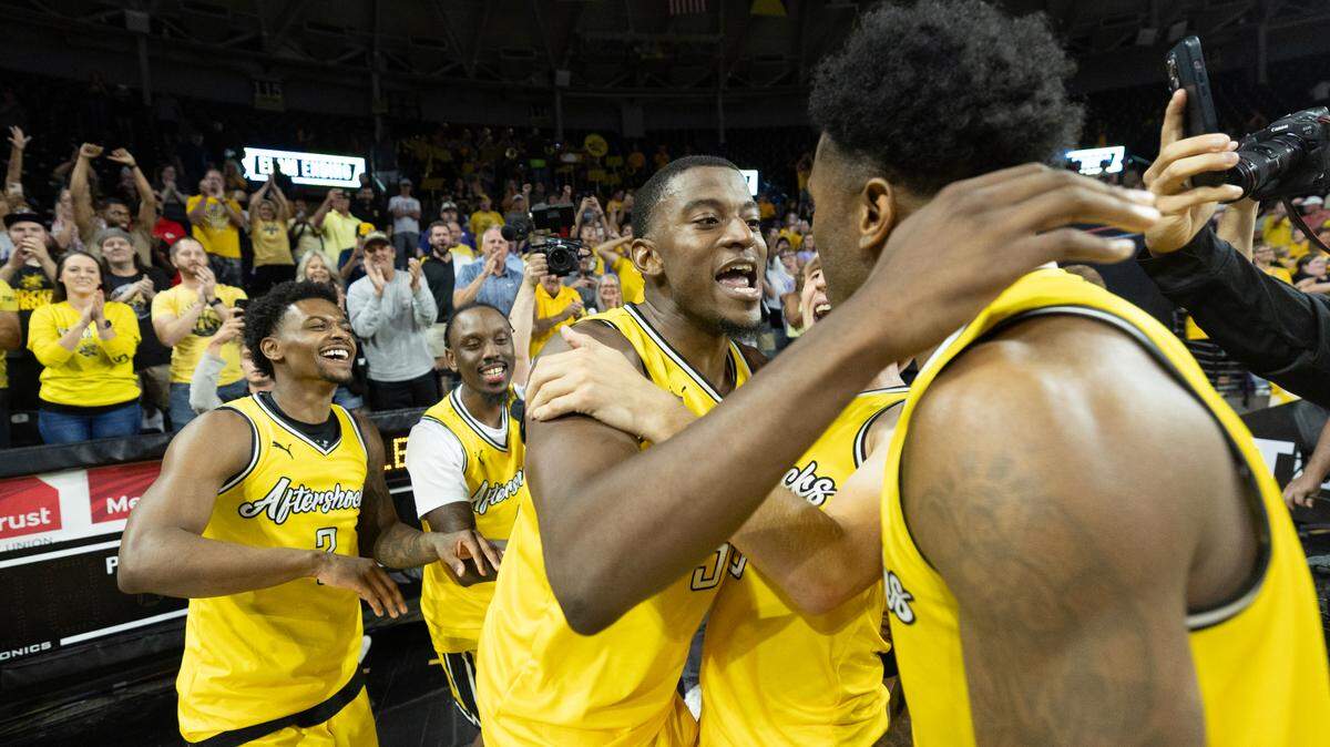 Trey Wade of the Aftershocks is mobbed by teammates after hitting the game winning shot against the Beale Street Boys during The Basketball Tournament on Friday night. The Aftershocks were down by by 19 in the second half before completing a comeback with members of the 2013 Wichita State Final Four team watching from behind the bench. 