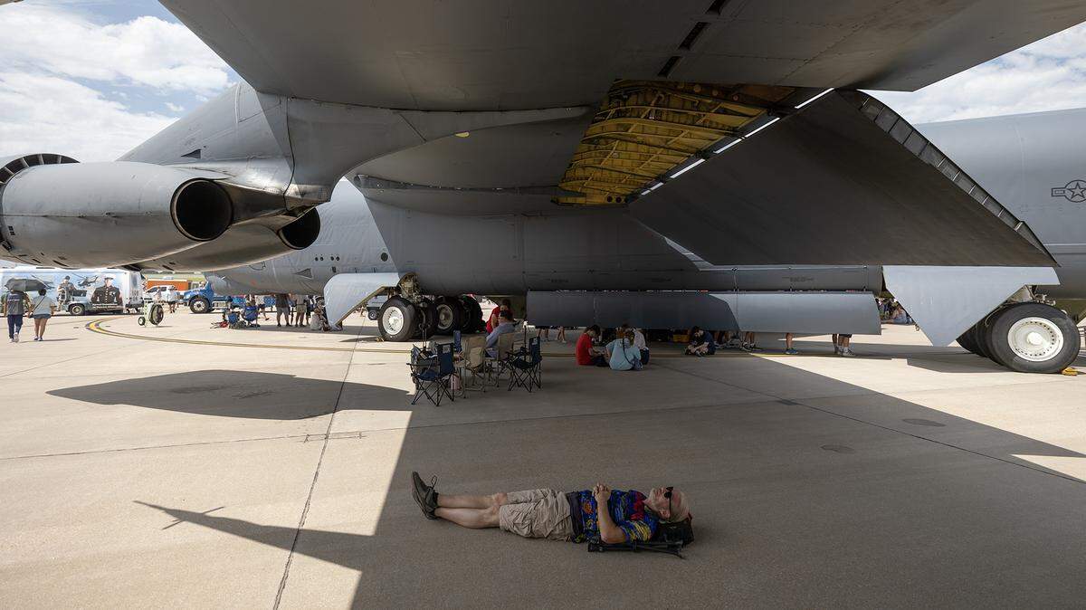An attendee of Saturday’s airshow at McConnell Air Force Base seeks relief from the heat under the wing of a B-52 bomber. More than 100 people were treated for medical issues, most heat-related, at the airshow.