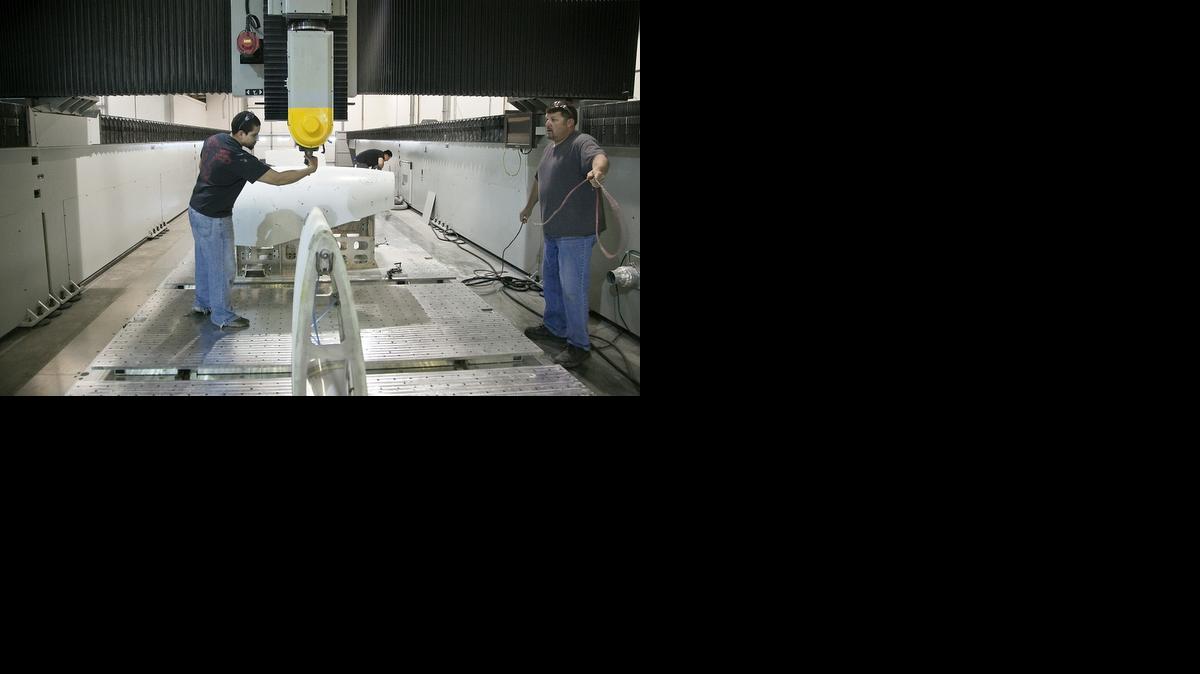 Chris Rosenstiel, left, and Trent Cantrell work on a 50-foot-long five-axis CNC machine at Leading Edge Aerospace in April 2014. The company’s facility, equipment and business operations are up for auction this month.