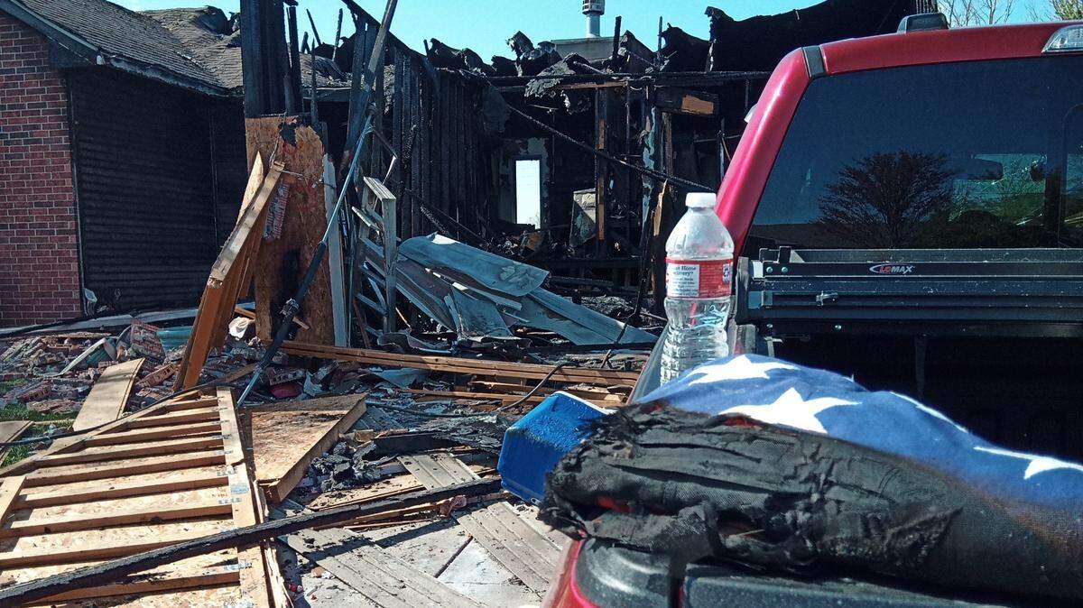 A charred American flag sits on the tailgate of a burned pickup in front of the West Wichita house that exploded Sunday.