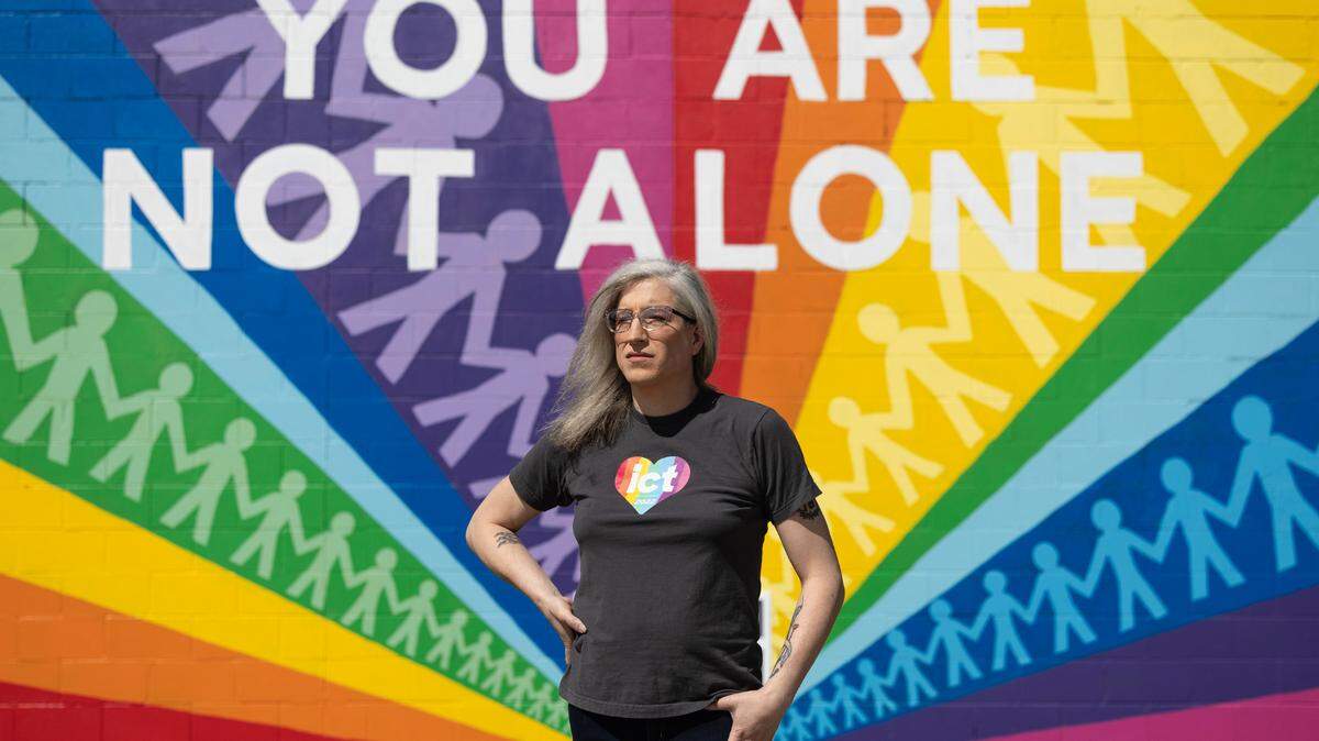 Abi Boatman (she/her) stands in front of the Pride mural at Reverie Roasters coffee shop in Wichita. Boatman is an Air Force veteran, small business owner and a transgender Kansan.