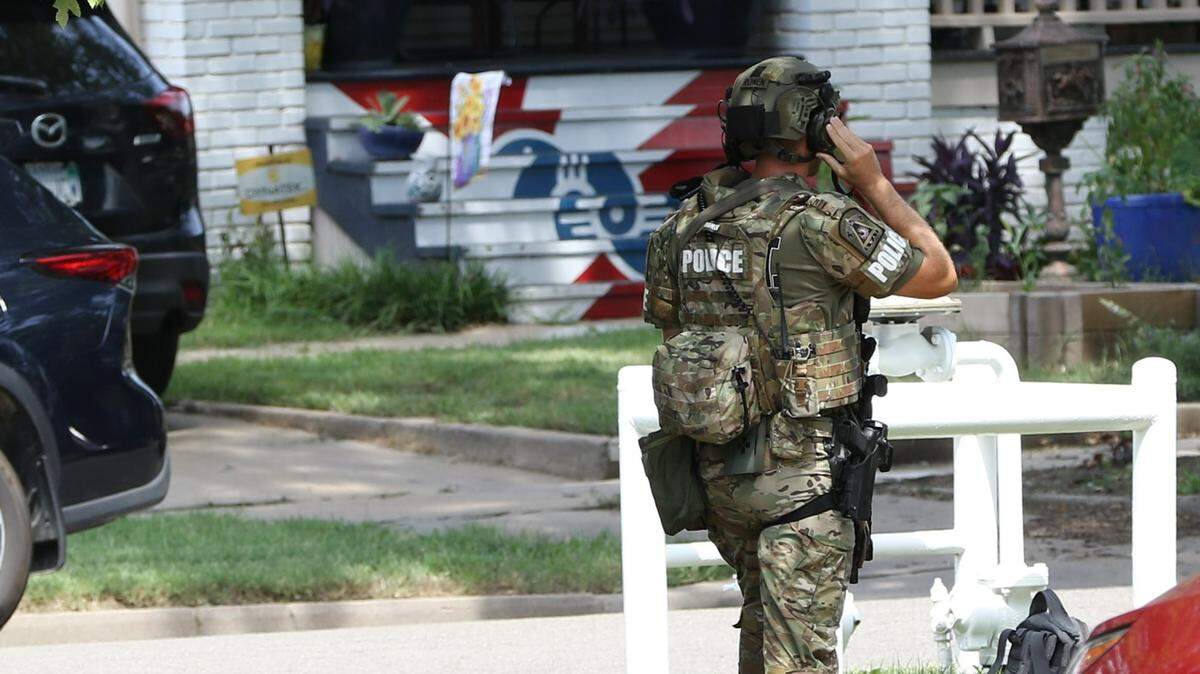 An officer is in tactical gear at a standoff Tuesday in the 1200 block of North Woodrow. The standoff with an armed man started while police were investigating the deaths of two people who were found dead in a home a block to the south. The man was eventually taken into custody.