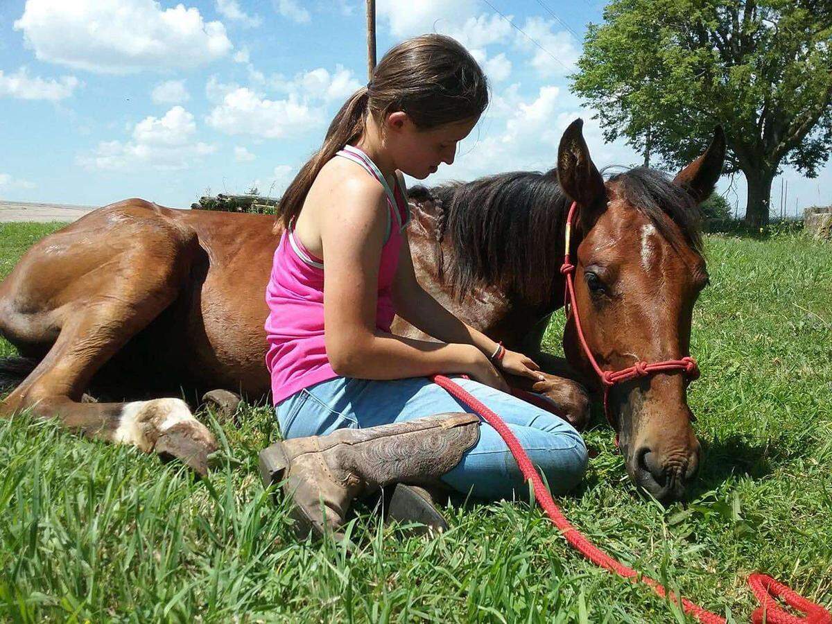Emma Brungardt sitting next to her mustang, Big Guy, which she trained after getting him to lay down for the first time. She trained multiple mustangs before her death in an Oct. 4 accident. She was 19.