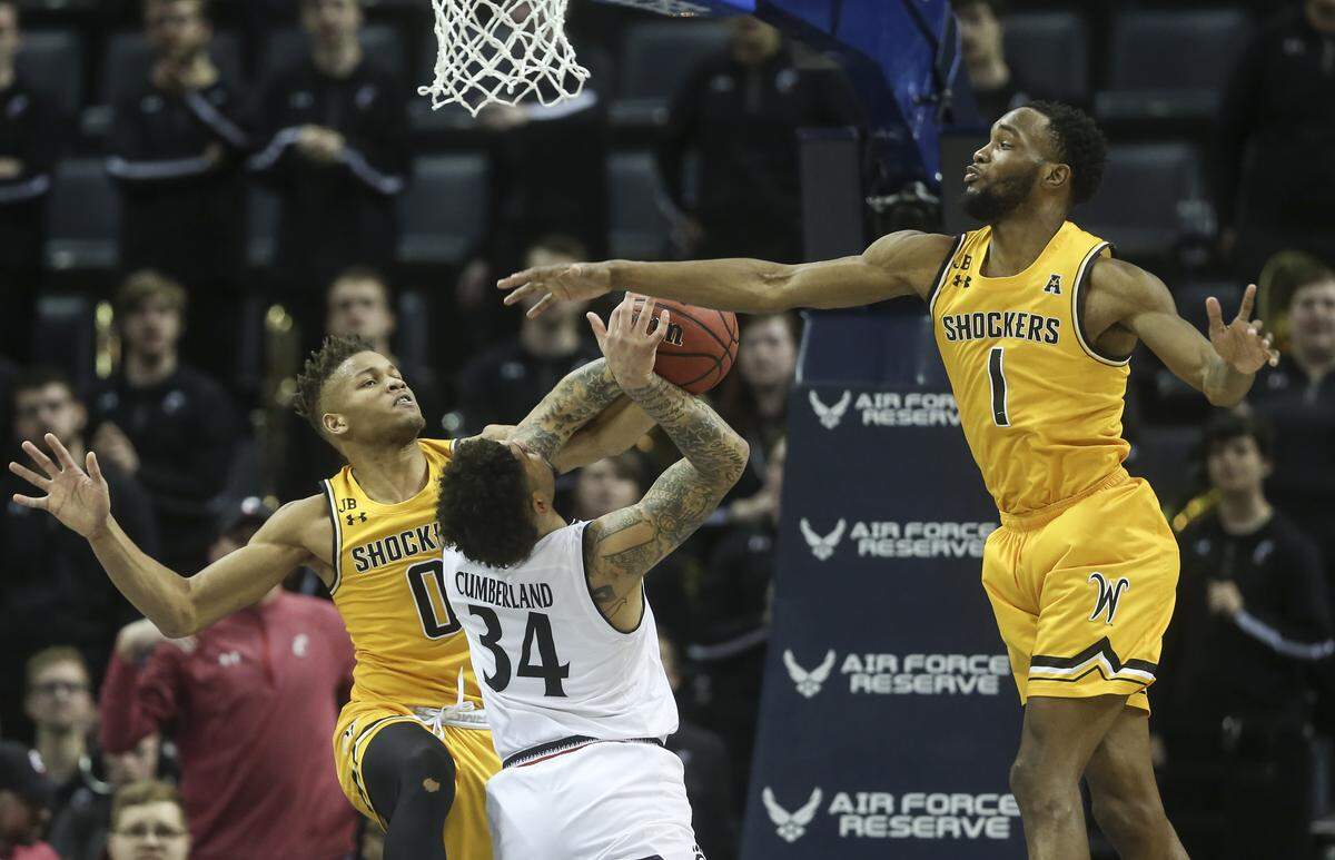 Wichita State guard Dexter Dennis, left, and forward Markis McDuffie defend Cincinnati guard Jarron Cumberland during the second half of their American Athletic Conference semifinal game in Memphis on Saturday.