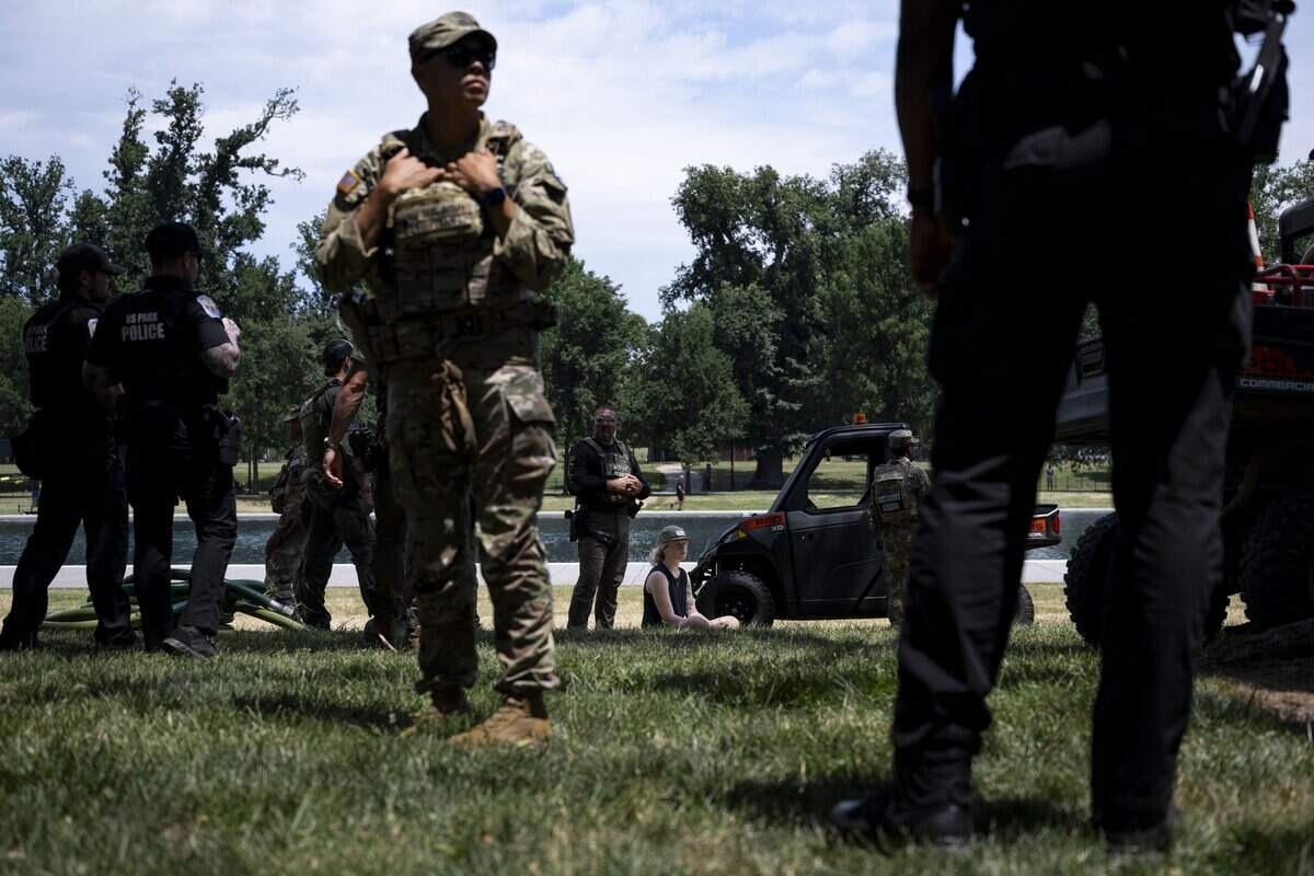 A young woman sits on the grass as she is detained before being issued a ticket after allegedly reaching into the reflecting pool and removing a piece of the coating that has peeled off at the Lincoln Memorial Reflecting Pool following the completion of recent renovations in Washington, DC, on June 22, 2026. US President Donald Trump on Monday threatened jail time for anyone seeking to damage one of his signature renovation projects, the Reflecting Pool at the Lincoln Memorial in Washington, whose overhaul has become a political flashpoint. Trump brought in contractors to drain the 610-meter pool and repaint it "American flag blue." But soon after completion of the work the coating has begun to peel off and algae turned the pool's water a mucky green -- setbacks the president blamed on vandals, without providing evidence. (Photo by Kent Nishimura / AFP via Getty Images)