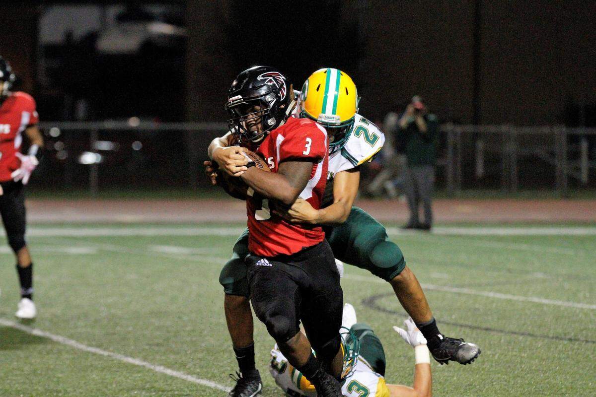 Bishop Carroll’s Phoenix Smith tries to bring down Heights’ K’Vonte Baker during the Golden Eagles’ 36-20 win over the Falcons on Friday. (Sept. 7, 2018)