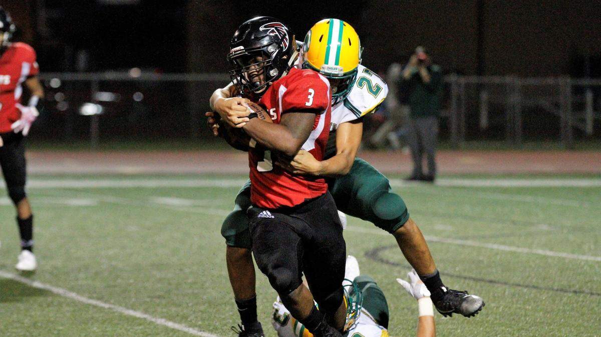 Bishop Carroll’s Phoenix Smith tries to bring down Heights’ K’Vonte Baker during the Golden Eagles’ 36-20 win over the Falcons on Friday. (Sept. 7, 2018)