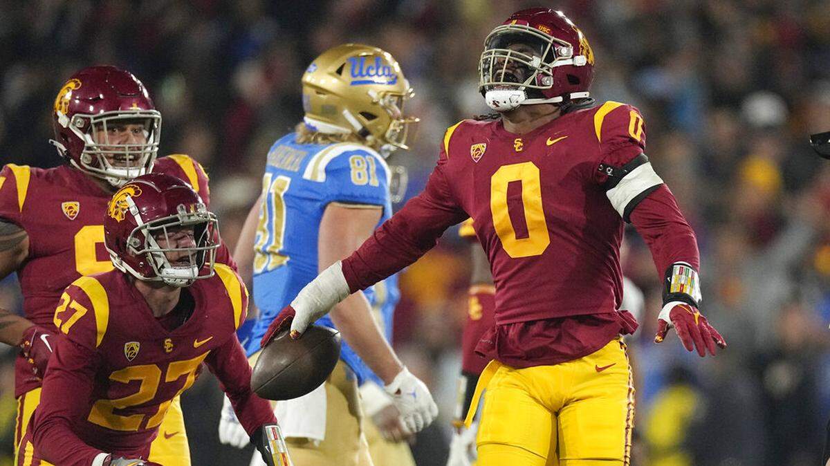 Southern California defensive end Korey Foreman, right, celebrates with defensive back Bryson Shaw, second from left, and defensive lineman Brandon Pili after intercepting a pass during the second half of an NCAA college football game against UCLA Saturday, Nov. 19, 2022, in Pasadena, Calif. (AP Photo/Mark J. Terrill)