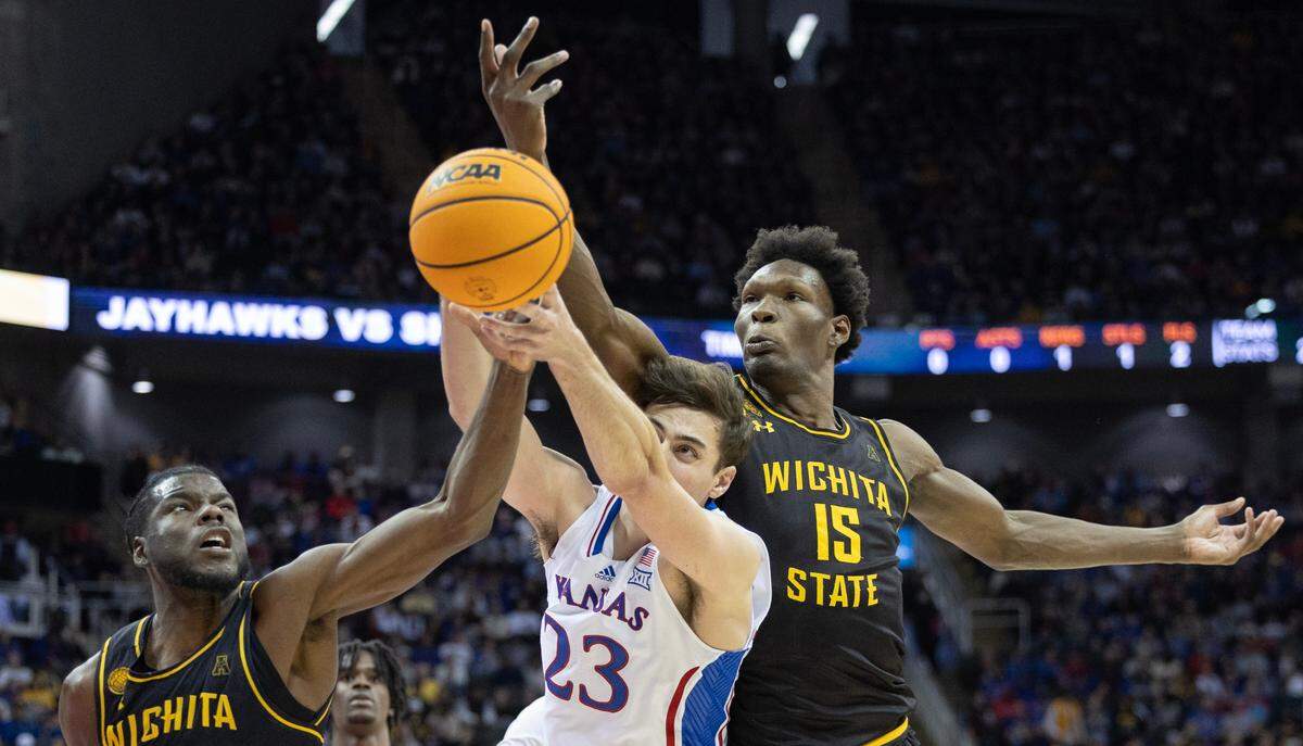 Kansas’ Parker Braun tries to get a handle on a rebound against Wichita State’s Quincy Ballard, right, and Dalen Ridgnal during the second half of their game at the T-Mobile Center on Saturday. 
