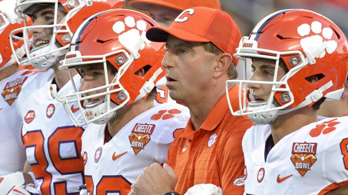 FILE - Clemson head coach Dabo Swinney, second from right, walks with players on the field before the Cheez-It Bowl NCAA college football game against Iowa State, Wednesday, Dec. 29, 2021, in Orlando, Fla. The perpetually positive Swinney probably has more need for it these days with his team breaking in three new assistants including first-time Clemson coordinators on defense in Wes Goodwin and offense in Brandon Streeter. (AP Photo/Phelan M. Ebenhack, File)