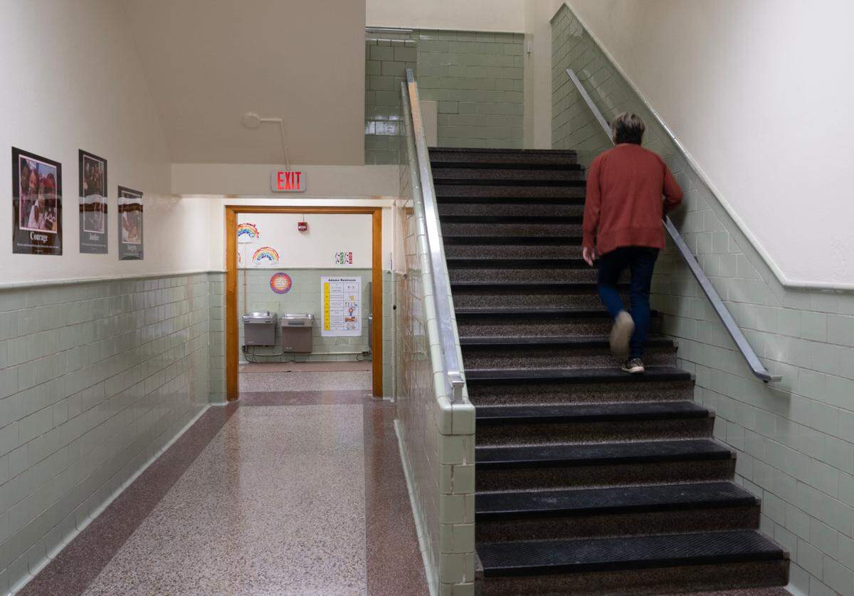Adams Elementary School Principal Stacy Burke walks up the stairs to the second floor. There are no elevators in the building and this year some fifth graders were moved downstairs because a teacher is teaching from a scooter.