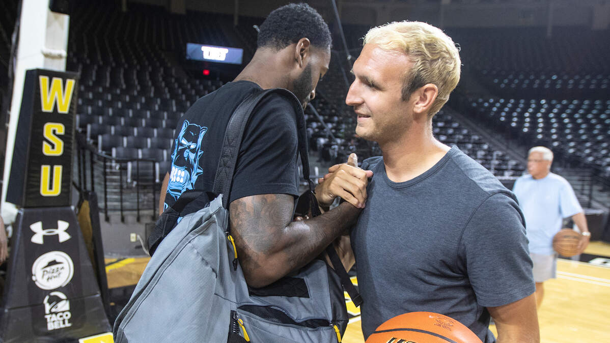 Former Shocker teammates Conner Frankamp (right) and Rashard Kelly (left) embrace at the start of the AfterShocks’ practice on Monday night.