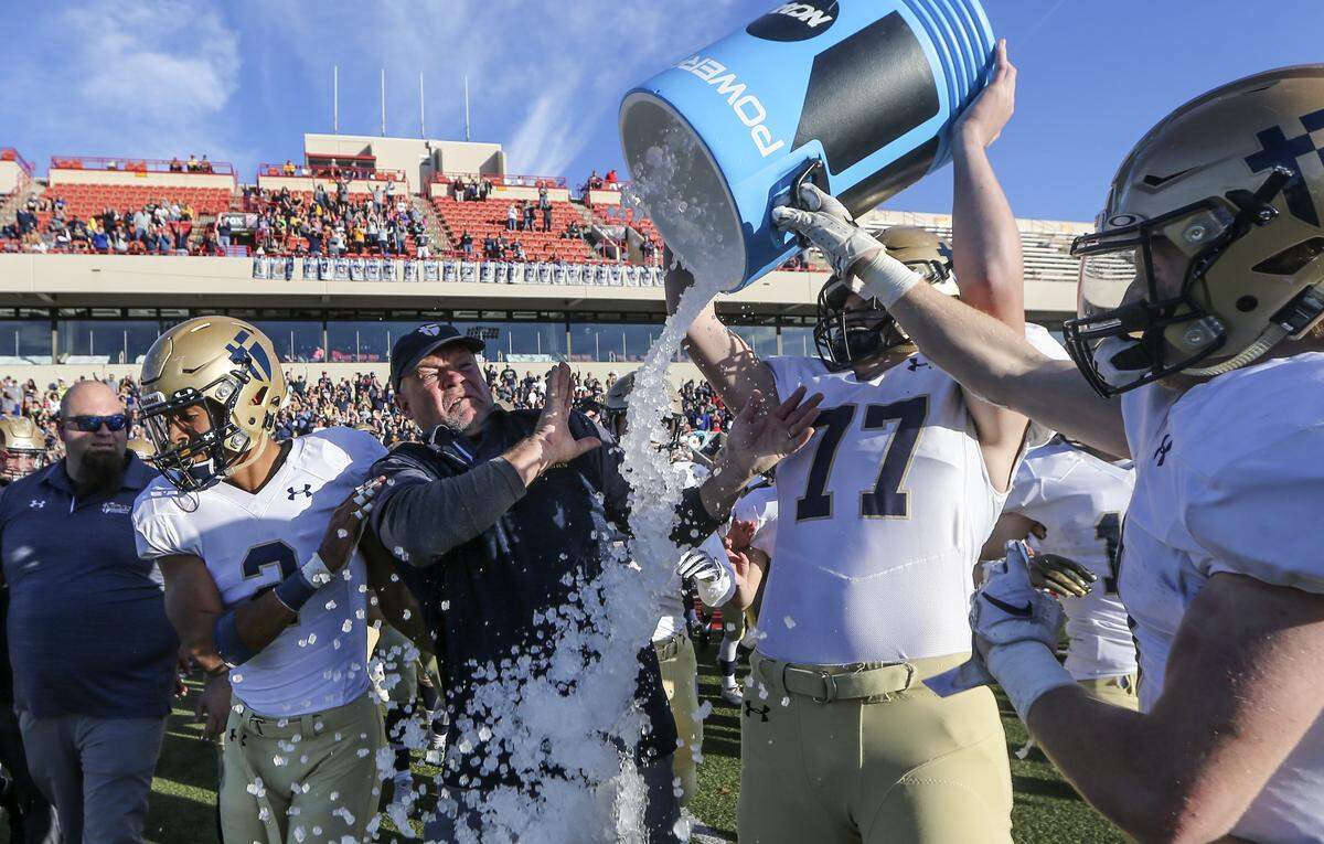 St. Thomas Aquinas coach Randy Drieling tries to avoid the ice bath after the Saints won the 5A state title over Wichita Northwest on Saturday in Pittsburg. 