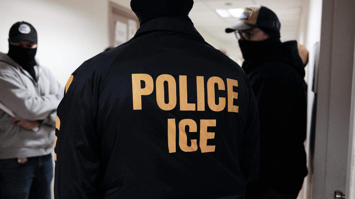 Masked federal agents wearing a Police ICE jacket,  stand in a hallway at the New York Federal Plaza Immigration Court inside the Jacob K. Javitz Federal Building in New York on March 17, 2026. US President Donald Trump has made deporting undocumented immigrants a key priority for his second term, after successfully campaigning against an alleged "invasion" by criminals. (Photo by CHARLY TRIBALLEAU / AFP via Getty Images)