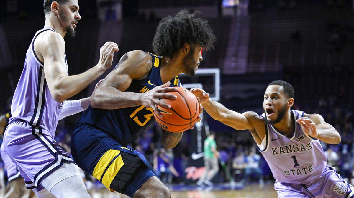 West Virginia forward Isaiah Cottrell (13) protects the ball from Kansas State guard Markquis Nowell (1) and forward Ismael Massoud, left, during the first half of an NCAA college basketball game in Manhattan, Kan., Monday, Feb. 14, 2022. (AP Photo/Reed Hoffmann)