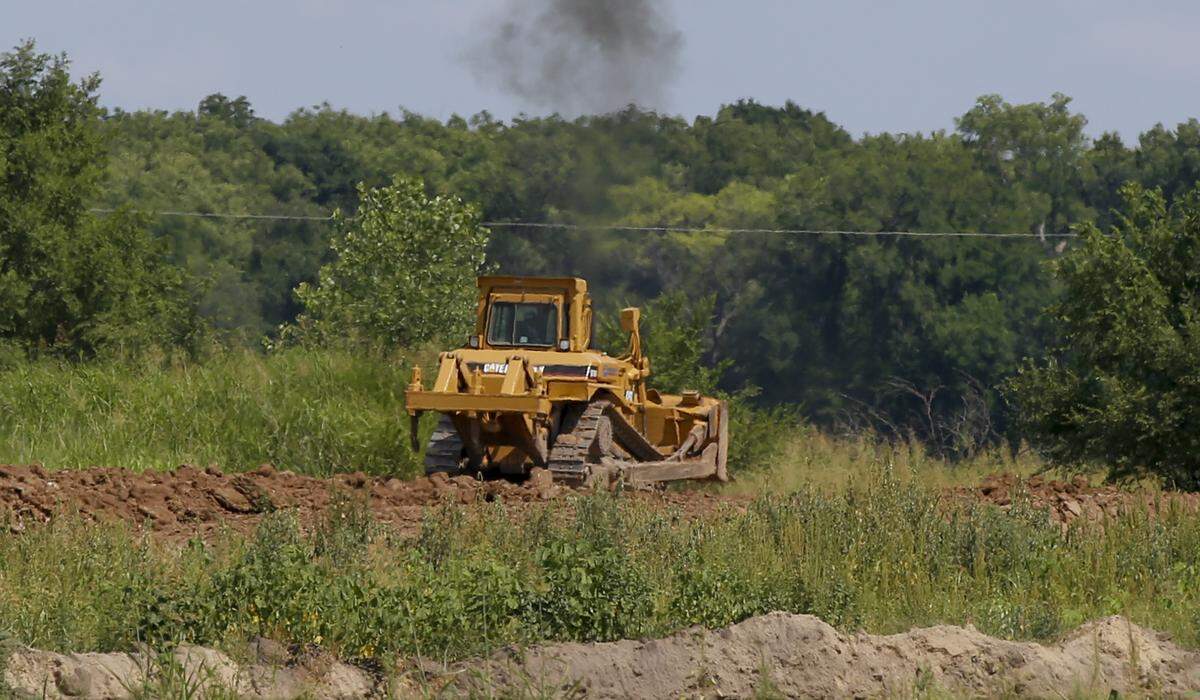 A tractor moves dirt around on land southwest from the corner of 55th and Clifton Tuesday. Homeowners across the street from the dirt and sand-mining operation complained at the Wichita city council meeting that they had to stay inside during the day because of the dust. The operation was just granted permission to expand. (July 10, 2018)