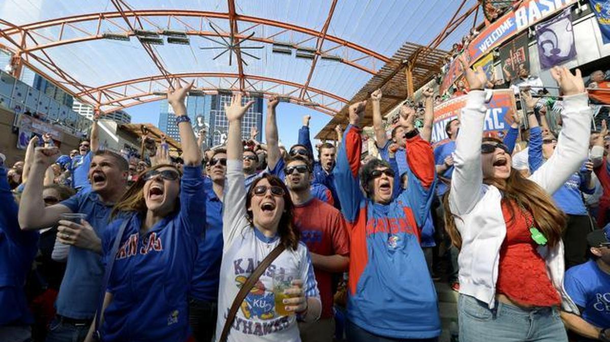 Fans at the Power and Light District watch on the big screen and cheer for the University of Kansas as they watch the closing seconds in their 77-70 overtime win against Oklahoma State during Thursday’s Big 12 Basketball Tournament game at the Sprint Center on March 13, 2014 in Kansas City.