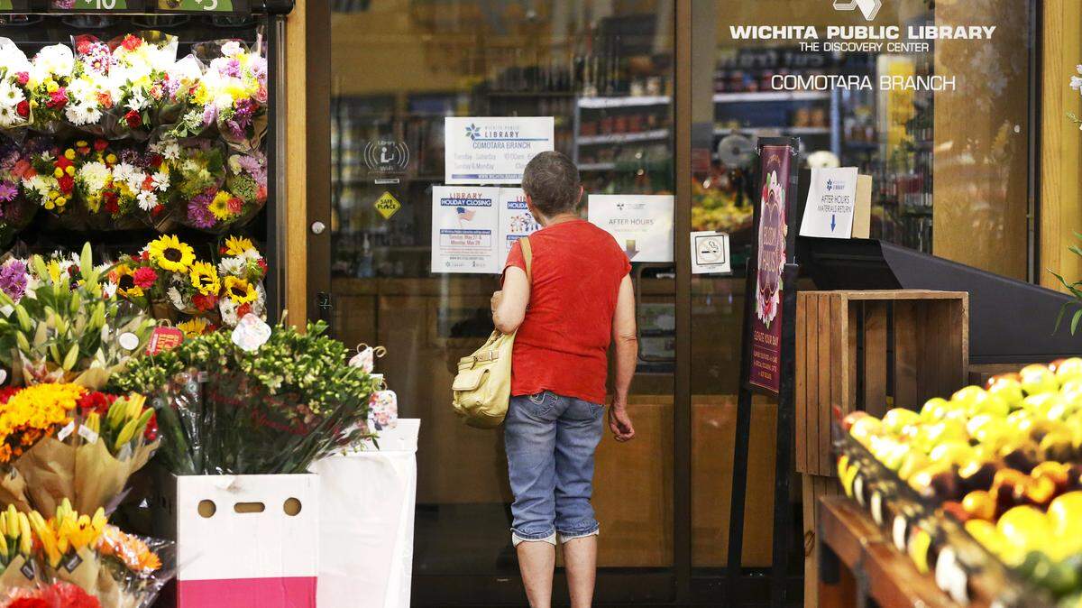 A shopper checks the hours at the Comotara branch of the Wichita Public Library inside the Dillons store at 21st and Rock on Monday. The small library might be closing. (May 14, 2018)