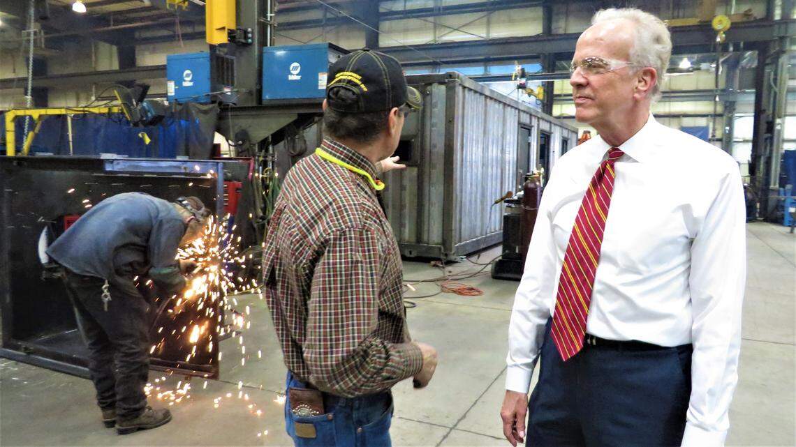 Sen. Jerry Moran (right) gets a lesson in metalwork from Jorge Martinez of JR Custom Metal Products, while William Wille welds in the background.