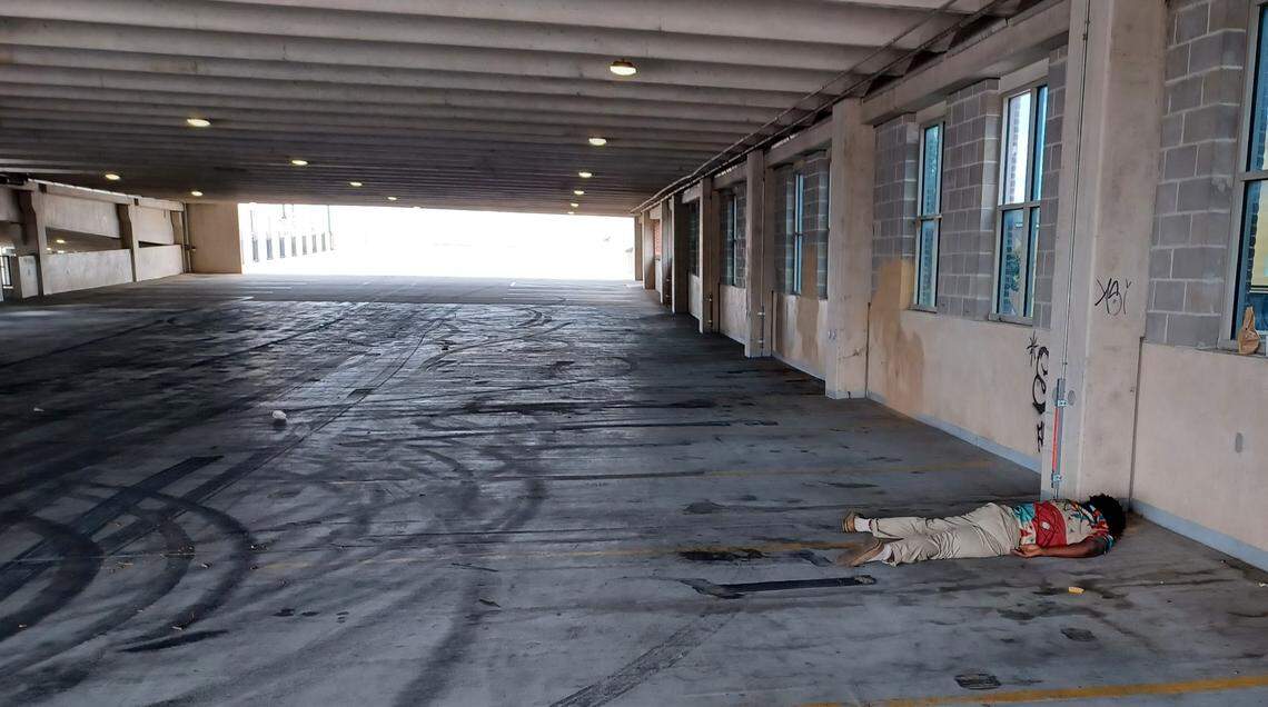 A homeless man sleeping in the parking garage at Old Town Square, which has become a makeshift, inadequate refuge.