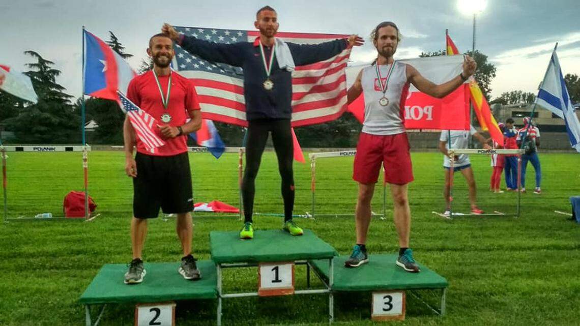 Kansas’ Aaron Yoder (center) poses after winning a world championship in retrorunning or backward running.