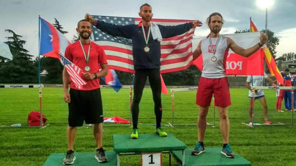 Kansas’ Aaron Yoder (center) poses after winning a world championship in retrorunning or backward running.