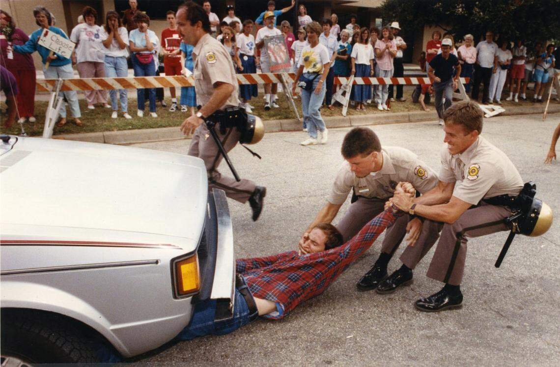 Wichita police officers attempt to remove an abortion protester from under a car at the entrance to George Tiller’s clinic during the Summer of Mercy protest in 1991.