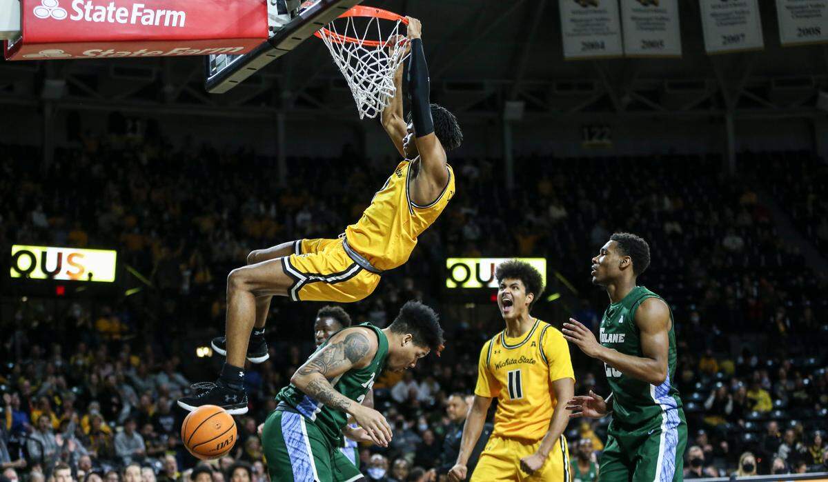 Wichita State’s Ricky Council IV hangs on the rim after throwing down a put-back dunk while teammate Kenny Pohto yells his approval during the first half of their game against Tulane on Wednesday night at Koch Arena.