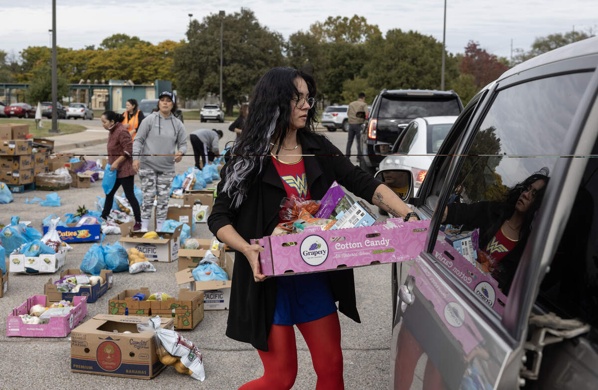 Volunteers give packages of food from the Kansas Food Bank warehouse to people in need outside the Evergreen Community Center on Friday.