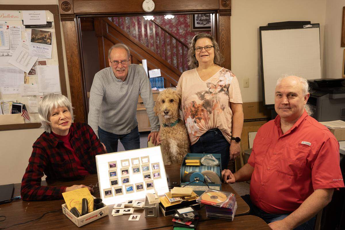 Midwest Historical and Genealogical Society board members, left to right, Ann Boll, Gary Clark, Julia Langel and Michael Urban gather around old media that can be digitized thanks to a donation by Melinda Lou Fultz.