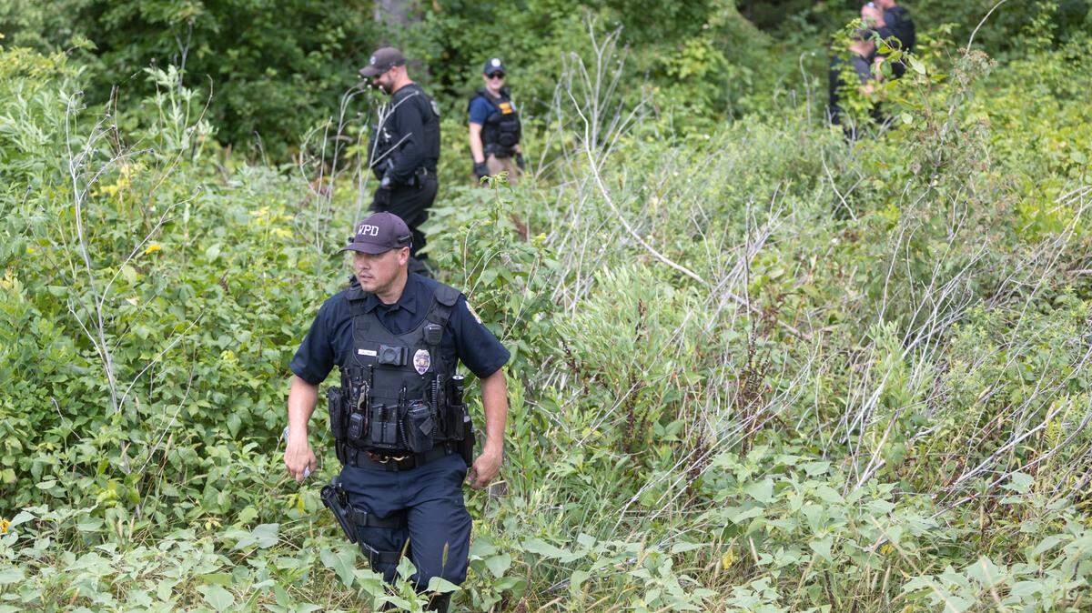 Law enforcement officers from multiple departments search a wooded area along Silver Lake Road near Cheney Reservoir on Monday. A man was arrested in the area after reports of a kidnapping and shooting in the area.