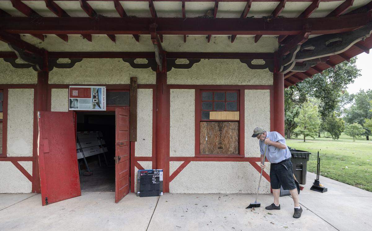 Former Lt. Gov. and Kansas Treasurer Lynn Rogers, who is spearheading the $200,000 effort to restore the Riverside pagoda, sweeps glass there Tuesday morning following a Monday evening vandalism incident that Rogers said also hurt a homeless man who likes to protect the pagoda.