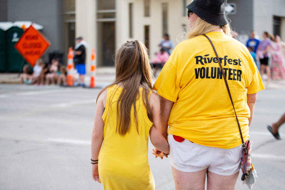 Two Riverfest attendees watch the Star Lumber Sundown Parade on the first day of Riverfest.