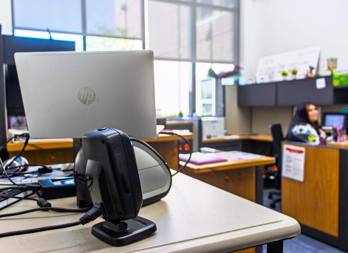 An employee mans the Hamilton Middle School front desk. Visitors ring the bell at the secured entrance and an office employee permits entry via a laptop in the main office.