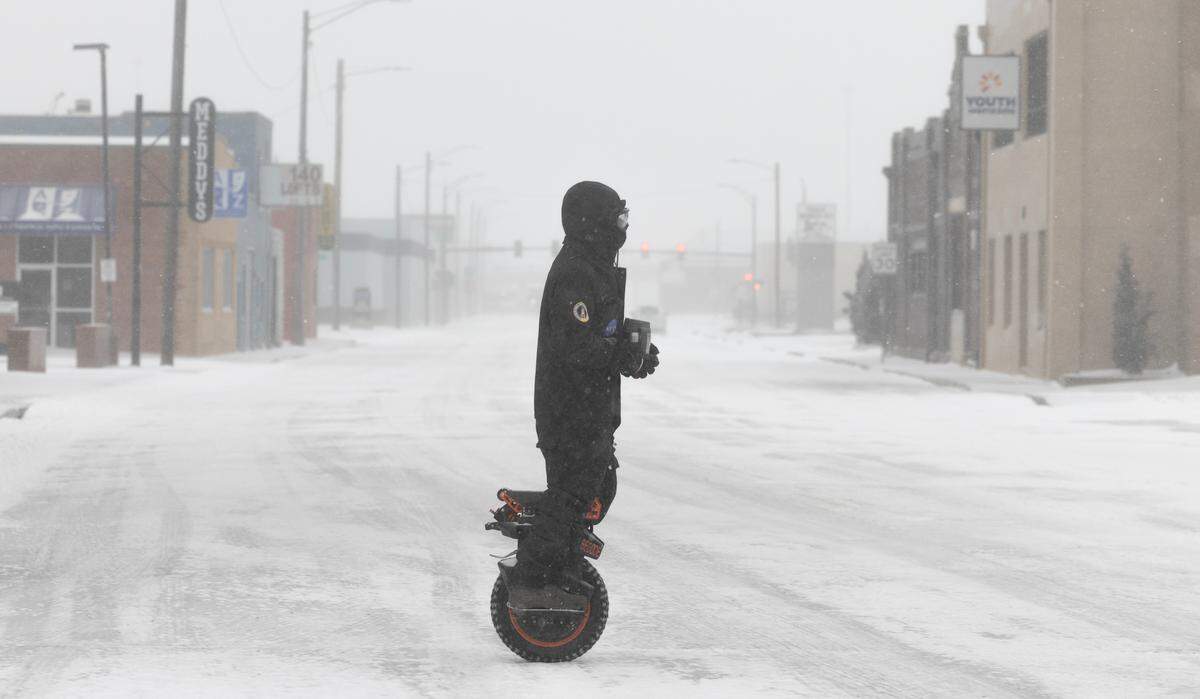Brenden Campbell makes his way through downtown Wichita on a one-wheel electric scooter during a severe winter storm on Sunday.