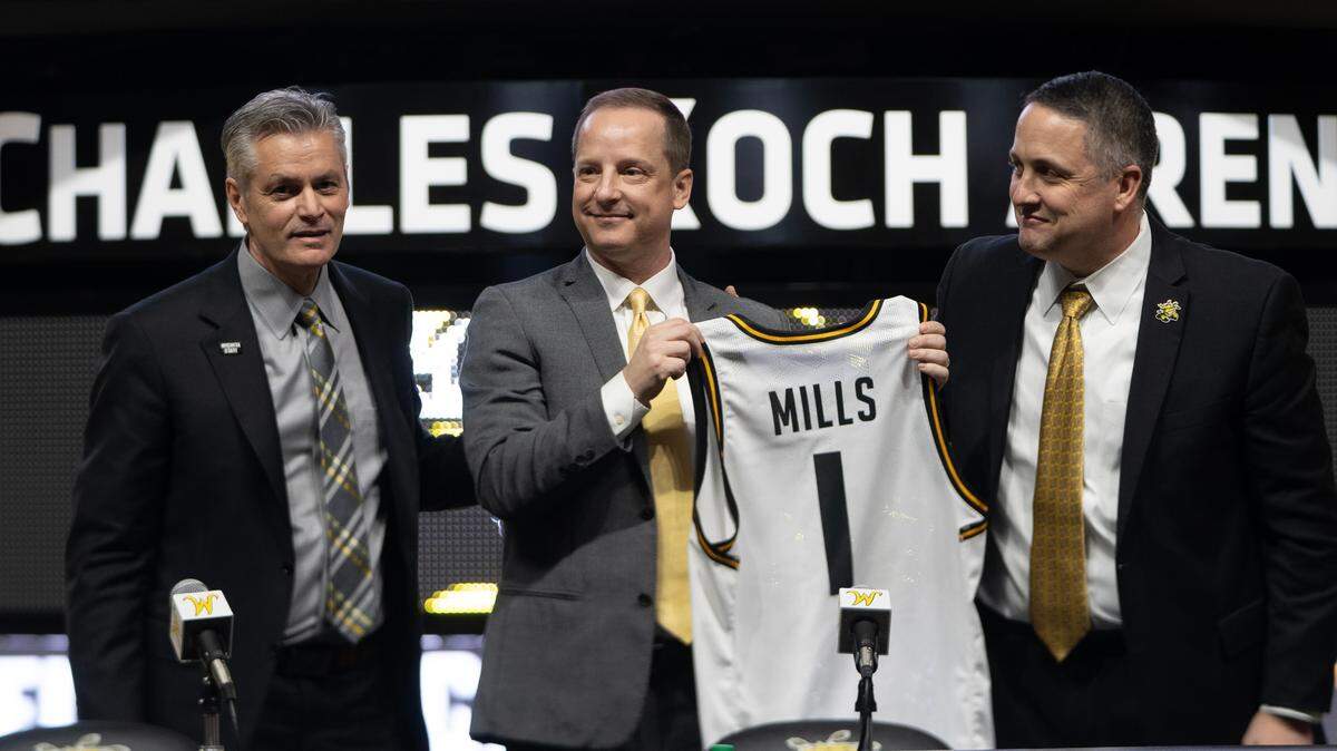 New Wichita State basketball coach Paul Mills, middle, holds up a Wichita State game jersey with his name on it alongside athletic director Kevin Saal, right, and university president Rick Muma. Mills comes to Wichita State from Oral Roberts University in Tulsa.