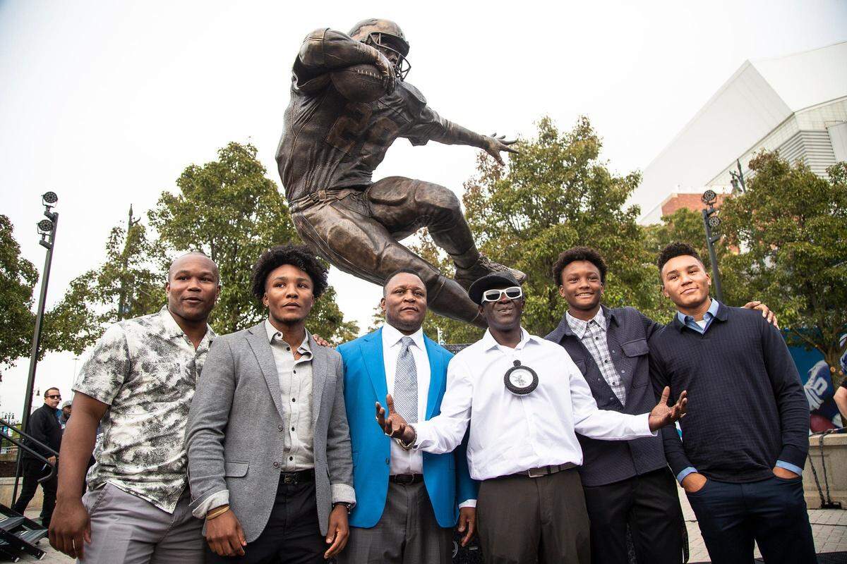 Barry Sanders and his family members pose for a photo with musician Flavor Flav next to the newly unveiled Barry Sanders statue outside of Ford Field in Detroit on Saturday, Sept. 16, 2023.