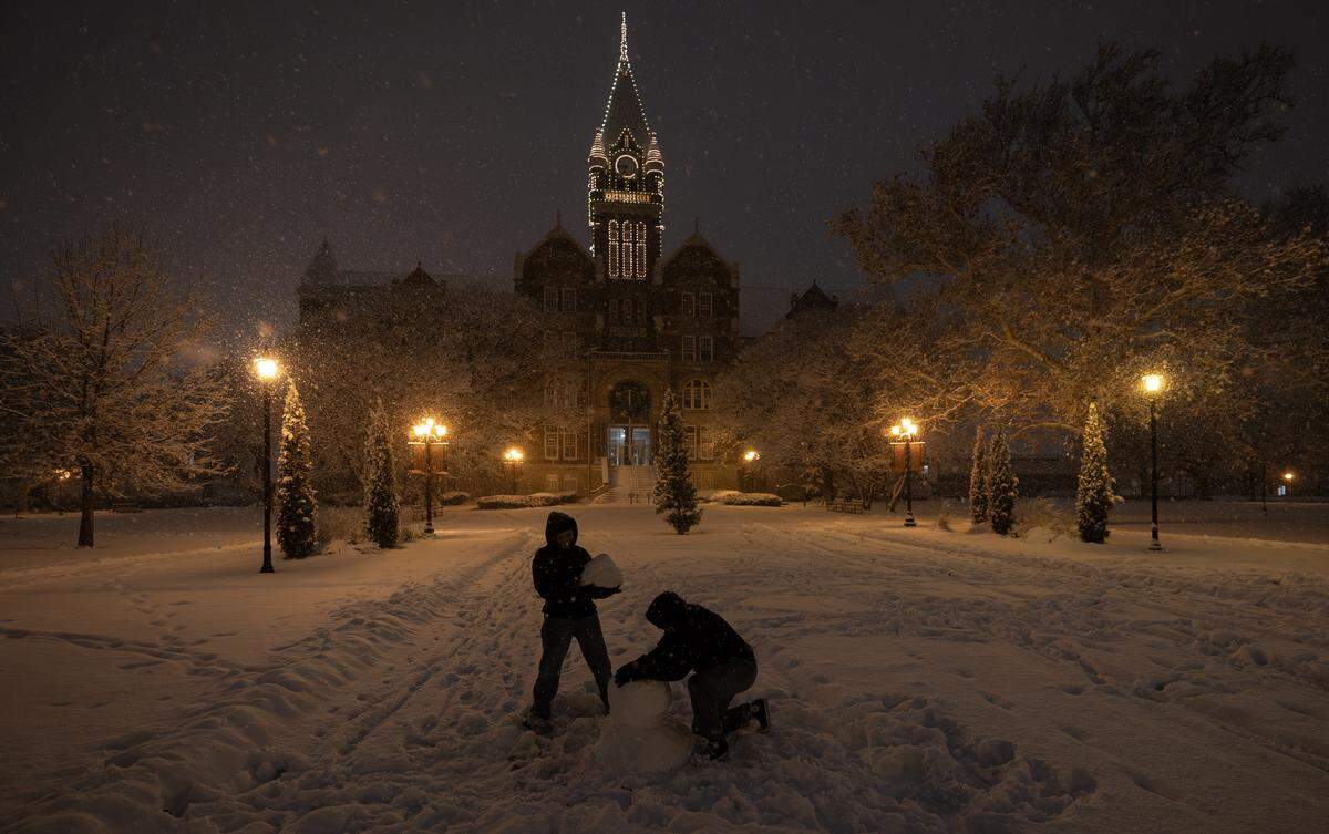 Two students work on a snowman at Friends University in January.