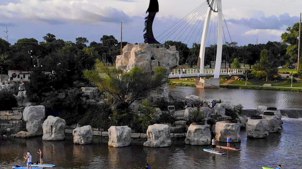 SUP Wichita leads a group of stand-up paddleboarders around the Keeper of the Plains.  This is the group's last weekend of regular operation. 