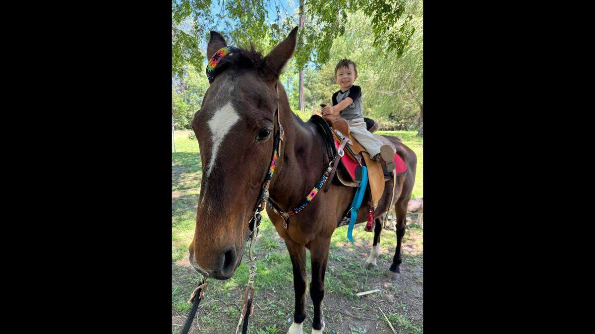 Milo sits on the back of his family horse, Torta.