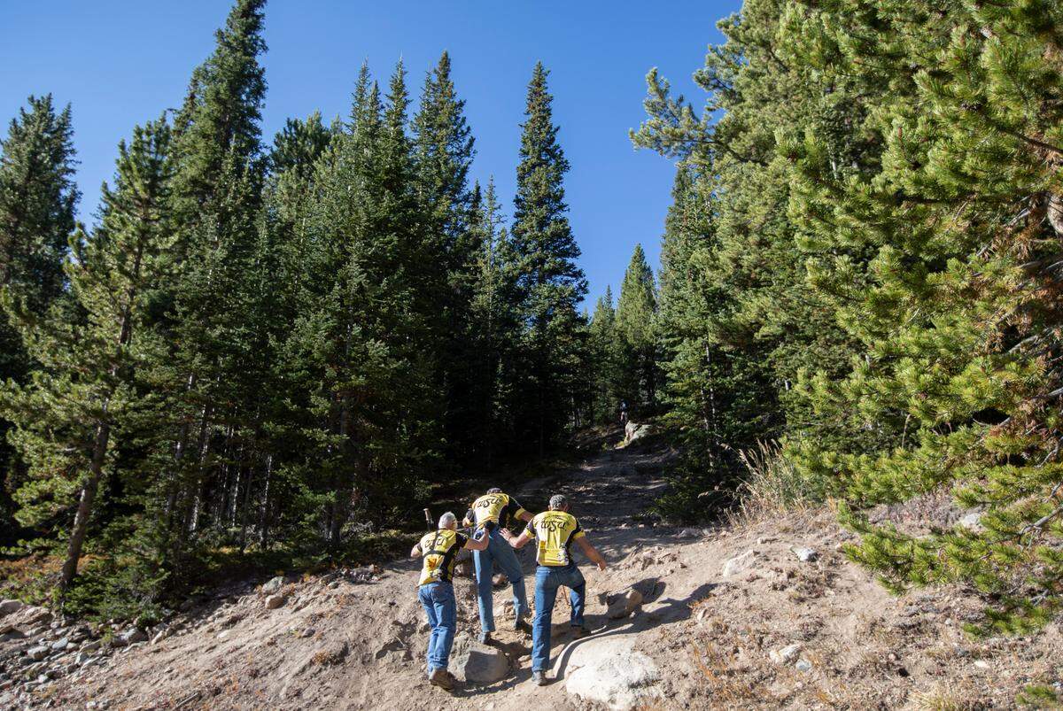 Rick Stephens, middle is helped by friends Kelly Harrison, right, and Paul Harrison, left, as they make their way up Mount Trelease on Saturday morning. Stephens was a survivor of a plane crash on the mountain in 1970 that was carrying members of the the Wichita State football team. Stephens was one of nine survivors in the crash that killed 31 people. During the previous week, the three men took part in a bicycle ride from Wichita to Colorado to remember the victims of the crash and raise money for a scholarship fund.
