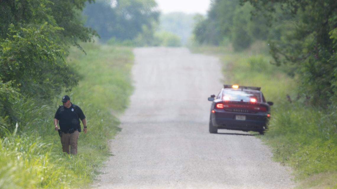 A Sedgwick County sheriff deputy searches a ditch along Sun City Road on Monday. A man was arrested in the area after reports of a kidnapping and shooting in the area.