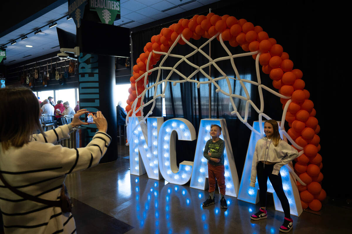 Fans pose in front of a NCAA sign on the concourse of Intrust Bank Arena in the first round of the 2025 NCAA Division I Men’s Basketball Championship.