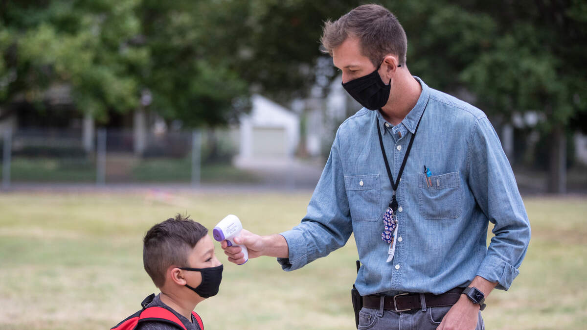 Baxter Schmidt, a teacher at Riverside Elementary, checked the temperature of a student as students began arriving for the first day of school in 2020. Just as the 2021-2022 school year began this week, Wichita teachers voted to approve a new union contract with USD 259.