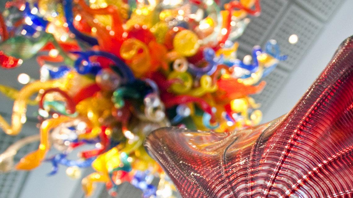 Rollin Karg inspects a piece of glass removed from Dale Chihuly's "Persian Seaform Ceiling," the colorful bridge of blown-glass pieces just inside the Wichita Art Museum. A second piece by Chihuly, "Confetti Chandelier," hangs in the museum's great room behind him. Karg and his staff at Karg Art Glass disassembled the work and cleaned each piece, plus the glass panels that make the top and bottom of the display, for the first time since its installation. (March 6, 2012)