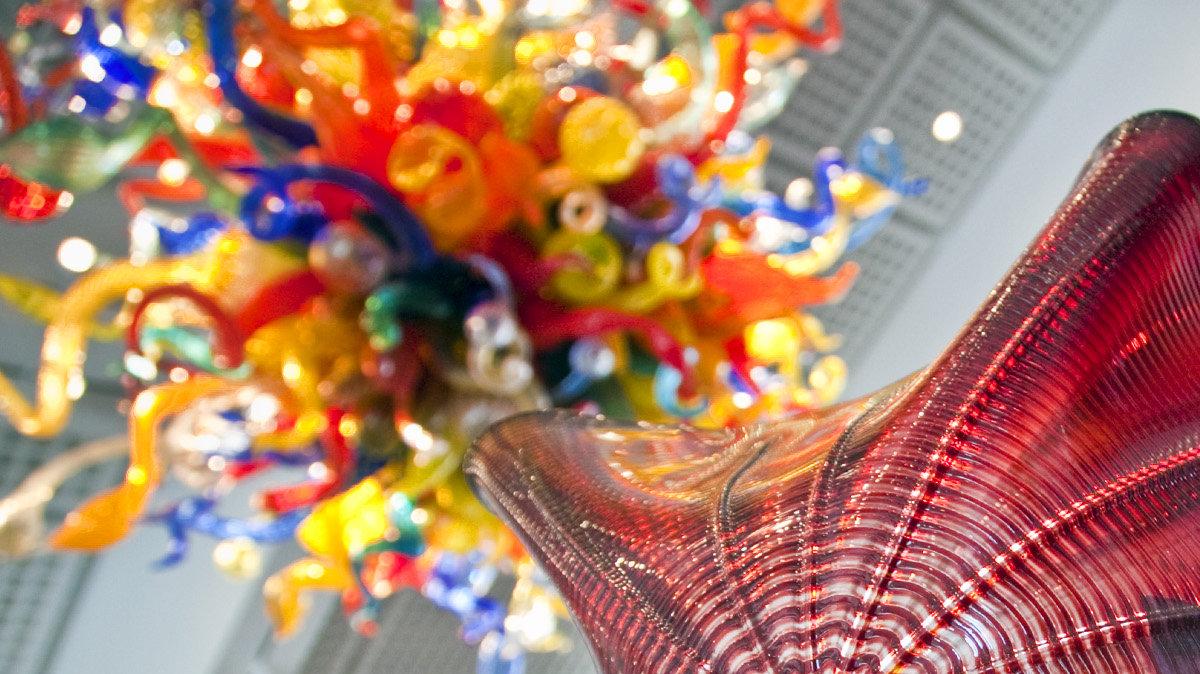Rollin Karg inspects a piece of glass removed from Dale Chihuly's "Persian Seaform Ceiling," the colorful bridge of blown-glass pieces just inside the Wichita Art Museum. A second piece by Chihuly, "Confetti Chandelier," hangs in the museum's great room behind him. Karg and his staff at Karg Art Glass disassembled the work and cleaned each piece, plus the glass panels that make the top and bottom of the display, for the first time since its installation. (March 6, 2012)