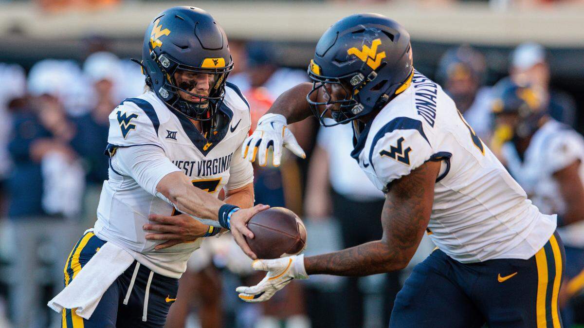 West Virginia Mountaineers quarterback Garrett Greene (6) hands off to running back CJ Donaldson Jr. (4) against the Oklahoma State Cowboys during the fourth quarter at Boone Pickens Stadium.